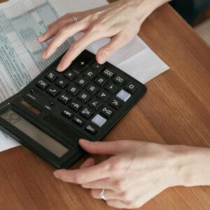 Person rechnet mit einem Taschenrechner die Kosten für eine Wasserenthärtungsanlage im Mehrfamilienhaus